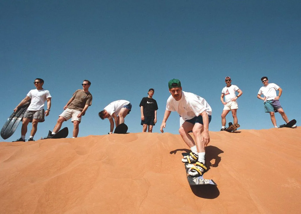 Men enjoying sandboarding in Dubai desert